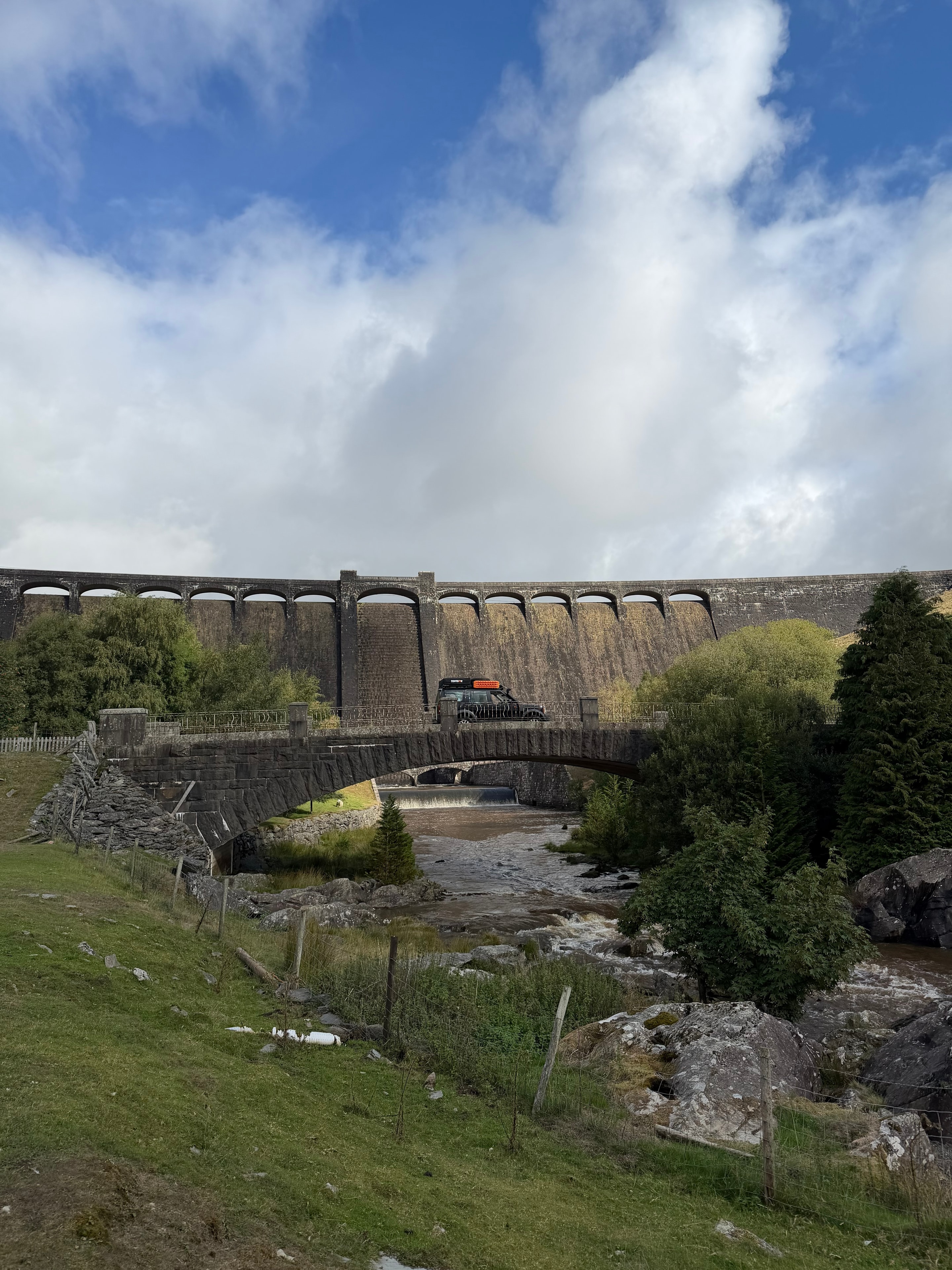 Land Rover crossing a bridge by a Welsh dam